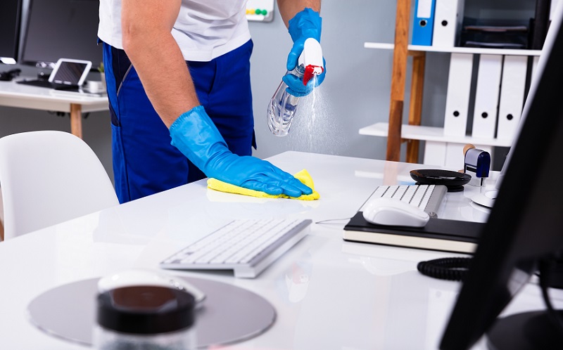 Janitor cleaning white desk in office
